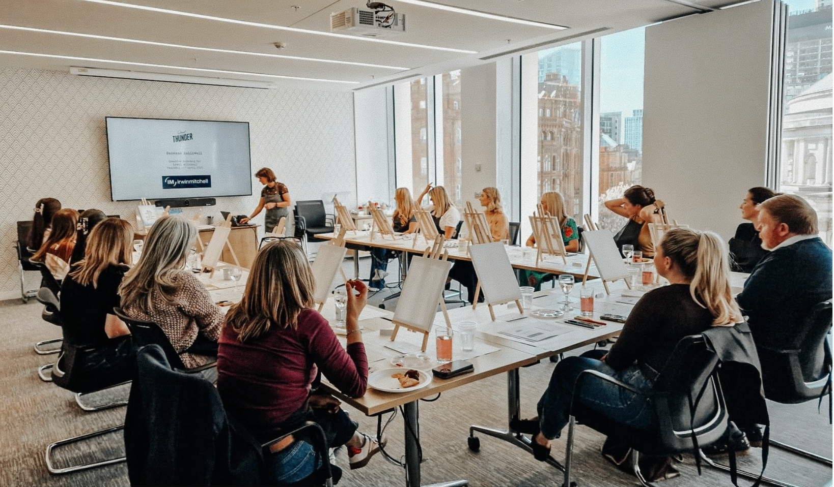 A professional team enjoying a Quiet Thunder painting workshop in a Manchester boardroom